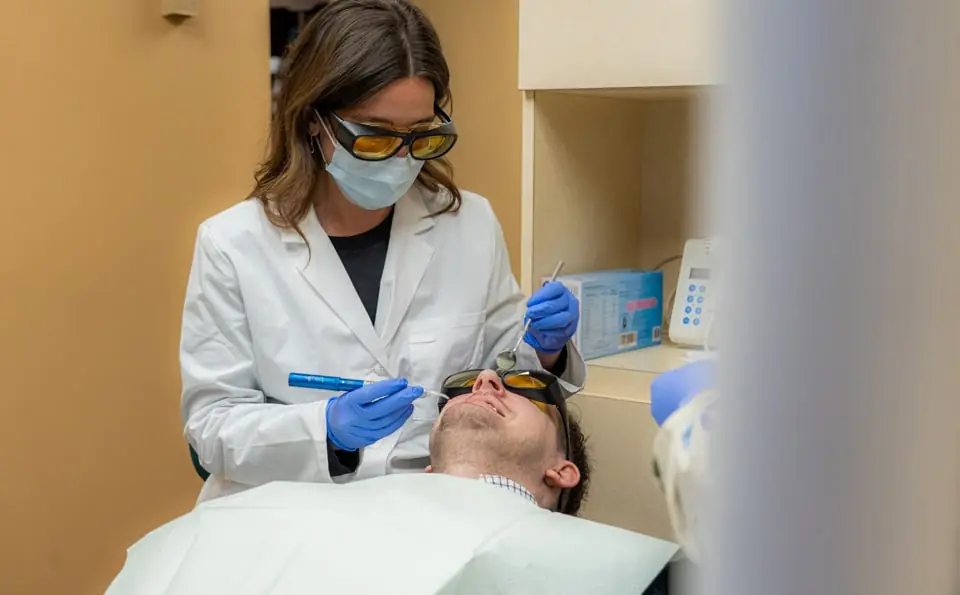 Dental hygienist cleaning a male patient's teeth